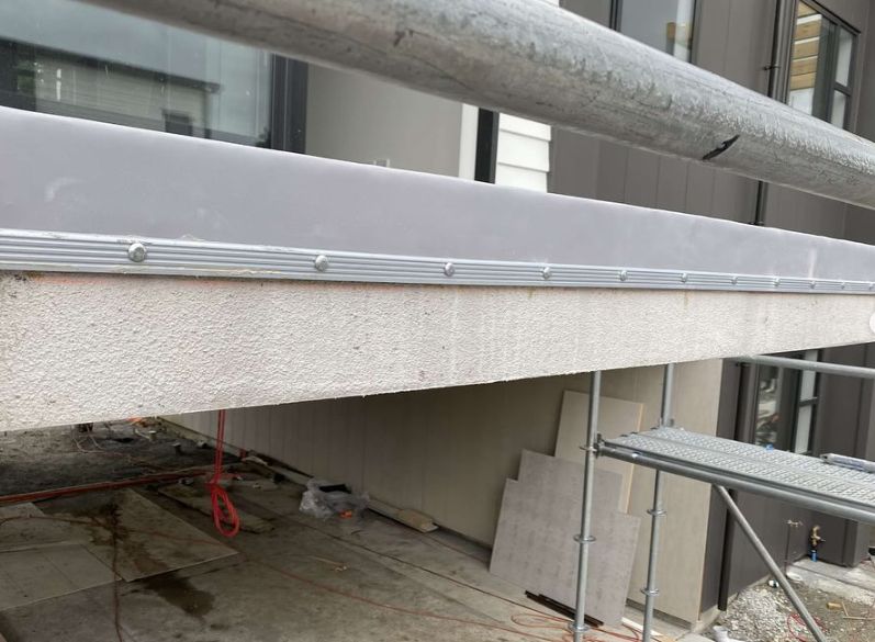Close view of a balcony edge with membrane, aluminium trim and screw fixings