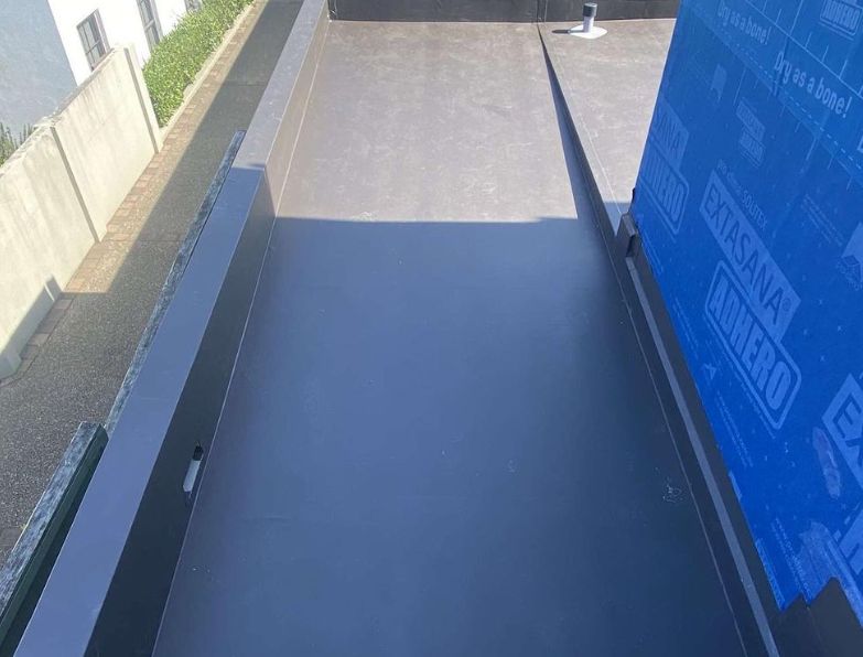 Dark grey membrane running between a parapet and a wrapped wall
